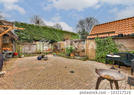 a backyard area with brick pavers and an outdoor fire pit in the middle, surrounded by green trees 103217528