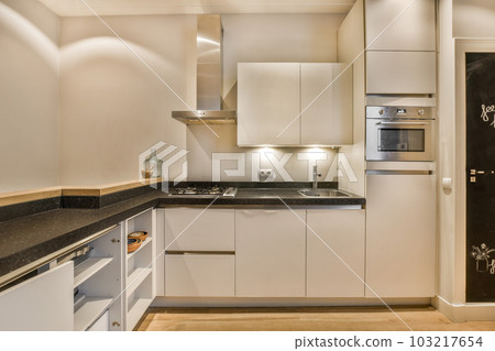 a kitchen with white cabinets and black counter tops on the counters in front of the sink is lit by light 103217654