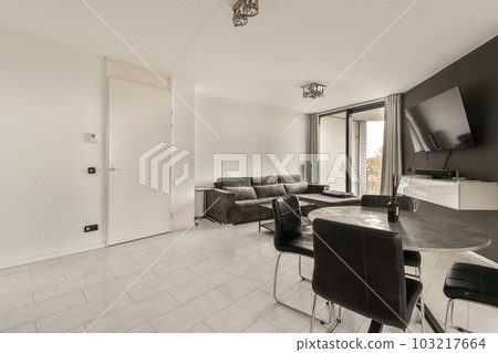 a living room with black and white furniture on the floor in front of a large flat screen tv mounted to the wall 103217664