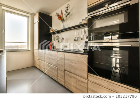 a modern kitchen with wood cabinets and stainless steel appliances on the counter tops, along with an open window looking out to the city 103217790