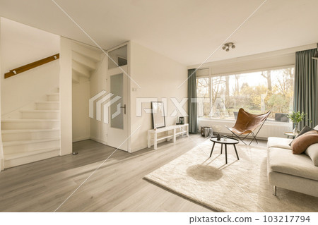 a living room with white walls and wood flooring in the center of the room, there is a tv on the wall a living room with white walls and wood flooring in the center of the room, there is a tv on the wall 103217794