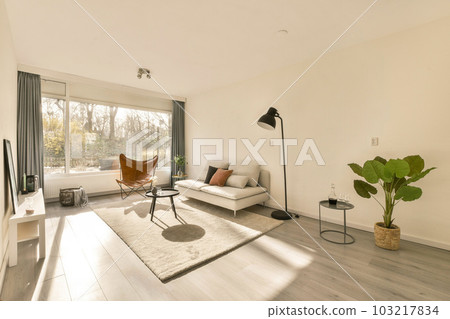 a living room with white walls and wood flooring in the center of the room, there is a large window looking out to 103217834