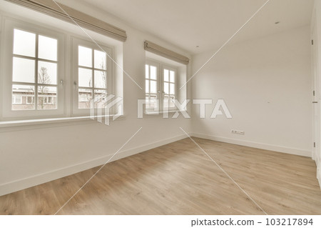 an empty room with white walls and wood flooring, there is a window in the wall to the right an empty room with white walls and wood flooring, there is a window in the wall to the right 103217894