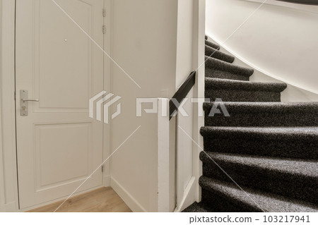 some stairs in a house with white walls and wood flooring on the bottom, there is an open door that leads to another 103217941