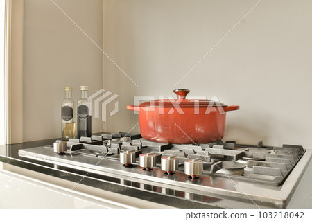 a pot on top of a stove with some cooking uts in front of it and an empty bottle next to it a pot on top of a stove with some cooking uts in front of it and an empty bottle next to it 103218042