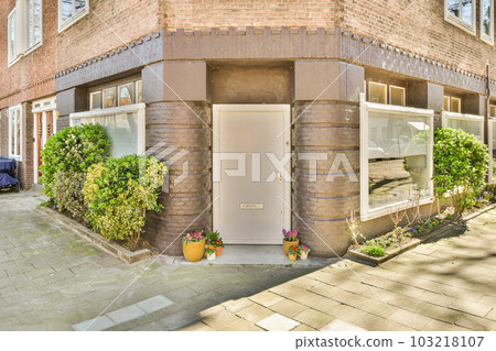a brick building with plants growing on the side and an open white door in front that leads to a parking lot a brick building with plants growing on the side and an open white door in front that leads to a parking lot 103218107
