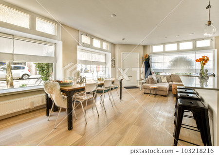 a living room with wood flooring and white walls in the center of the room is an open dining area 103218216