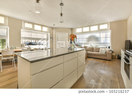 a kitchen and living room in a house with hardwood floors, white cabinets, wood flooring and large windows 103218237