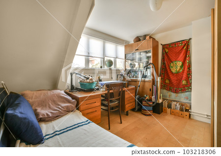 a bedroom with a bed, desk and window in the corner to the left is an open door that leads to another room 103218306