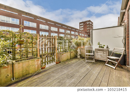 an outside area with wooden decking and plants on the side of the building in the background is a blue sky filled with white an outside area with wooden decking and plants on the side of the building in the background is a blue sky filled with white 103218415