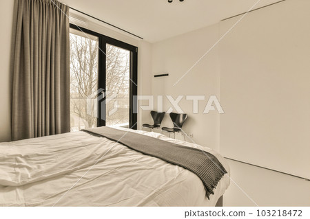 a bedroom with a bed, chair and large window looking out to the trees in the room is very clean a bedroom with a bed, chair and large window looking out to the trees in the room is very clean 103218472