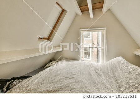 a bed in the corner of a room with an open window on one side and a white blanket on the other 103218631
