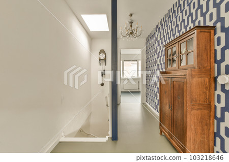 a long hallway with blue and white wallpapers on the walls, along an open door leading to another room 103218646