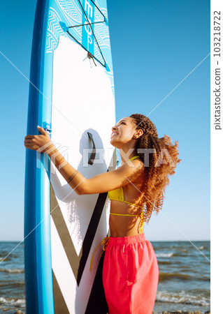 Woman surfer walks with a board on the sandy beach. Extreme sport. Travel, weekend, lifestyle. Woman surfer walks with a board on the sandy beach. Extreme sport. Travel, weekend, lifestyle. 103218722