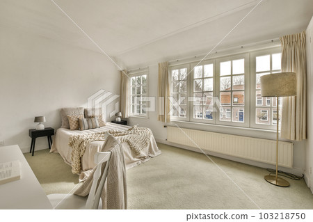 a bedroom with two beds and a desk in front of the window that overlooks out to the street outside 103218750