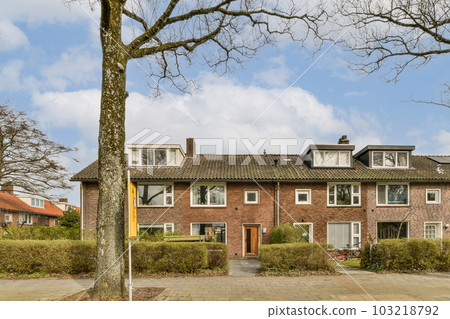 a house in the middle of an area with trees and bushes on either side of the building, there is a blue sky above 103218792