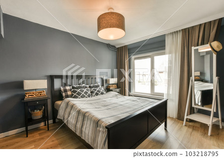 a bedroom with blue walls and wood flooring, including a black headboard on the side of the bed 103218795