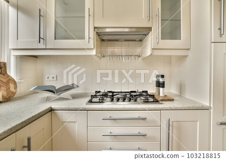 a kitchen with white cupboards and appliances on the counter top in front of the stove, which is being used for cooking 103218815