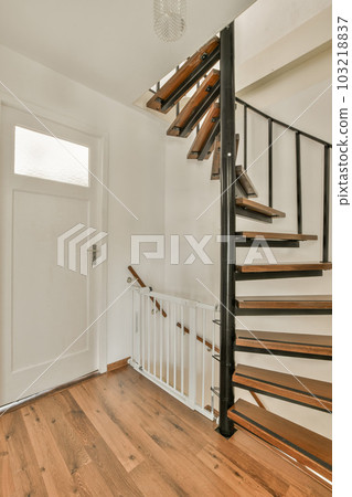 a staircase in a house with wood flooring and white walls on either side, there is an open door leading to the room 103218837