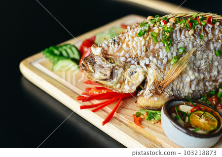 Red perch grilled in batter with vegetables and greens on wooden chop board isolated on black background side view Red perch grilled in batter with vegetables and greens on wooden chop board isolated on black background side view 103218873