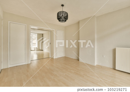 an empty room with white walls and wood flooring on one side, there is a light fixture hanging from the ceiling an empty room with white walls and wood flooring on one side, there is a light fixture hanging from the ceiling 103219271