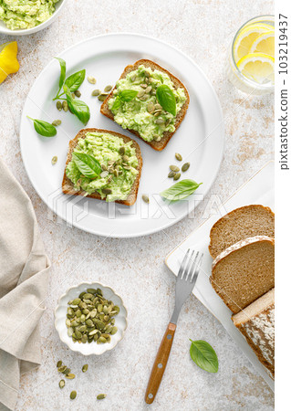 Avocado sandwich with pumpkin seeds. Healthy vegetarian avocado toast with rye bread for breakfast. Vegan menu. Top view Avocado sandwich with pumpkin seeds. Healthy vegetarian avocado toast with rye bread for breakfast. Vegan menu. Top view 103219437