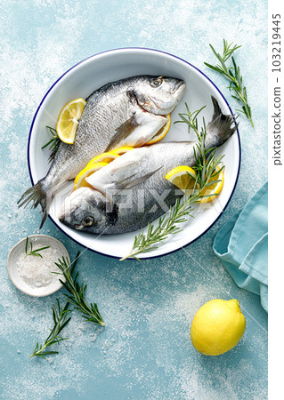 Fresh raw dorado fish cooking with lemon and rosemary. Sea bream, dorado. Seafood, healthy food. Top view 103219445
