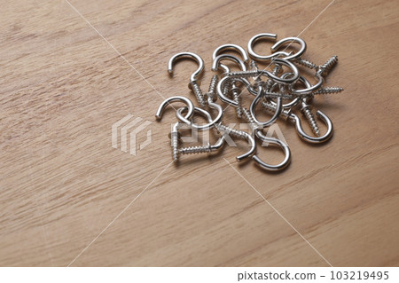 Screws with hooks photographed on a wooden table Screws with hooks photographed on a wooden table 103219495