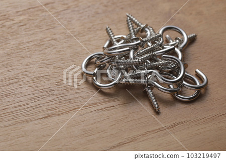 Screws with hooks photographed on a wooden table Screws with hooks photographed on a wooden table 103219497
