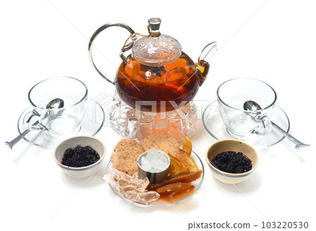 Glass tea pot with cups mulberry marmalade and crystalized fruits on white background Glass tea pot with cups mulberry marmalade and crystalized fruits on white background 103220530
