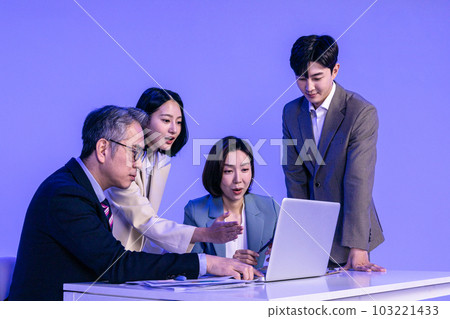 Asian Korean senior, middle aged and young male and female colleagues models in business attire, neon purple studio background, meeting while looking at a laptop Asian Korean senior, middle aged and young male and female colleagues models in business attire, neon purple studio background, meeting while looking at a laptop 103221433