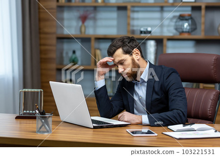 sad and depressed businessman in depression working inside modern office building, man in business suit with glasses and beard using laptop for work, boss disappointed with work result sad and depressed businessman in depression working inside modern office building, man in business suit with glasses and beard using laptop for work, boss disappointed with work result 103221531