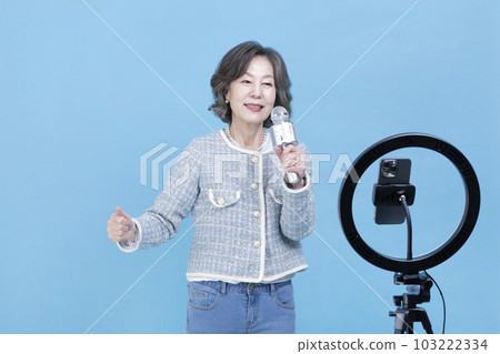 singing active young senior Korean Asian woman with smartphone, mobile karaoke concept 103222334