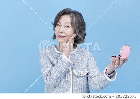 active young senior Korean Asian woman holding beauty cosmetic products 103222575