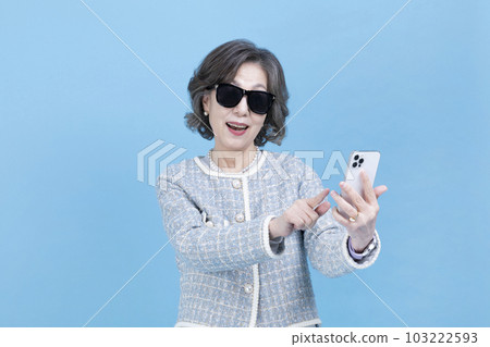 active young senior Korean Asian woman with sunglasses using smartphone active young senior Korean Asian woman with sunglasses using smartphone 103222593