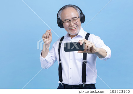 active young senior Korean Asian male listening to music with headset and smartphone 103223160