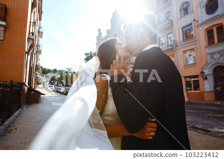 Bride and groom kisses tenderly in the shadow of a flying veil. Together. Wedding. Love. Bride and groom kisses tenderly in the shadow of a flying veil. Together. Wedding. Love. 103223412