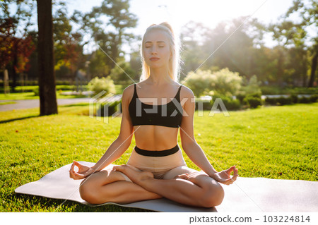 Young woman doing excercise at the public park. Fitness woman doing yoga exercises in the morning. Young woman doing excercise at the public park. Fitness woman doing yoga exercises in the morning. 103224814