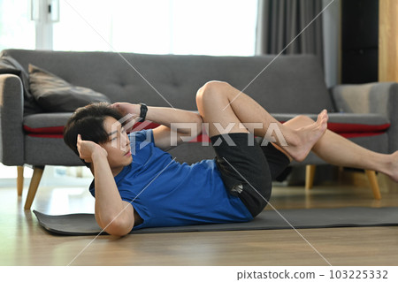 Sporty asian man doing sit ups exercise for abdomen on mat at home. Healthy lifestyle and sport concept 103225332