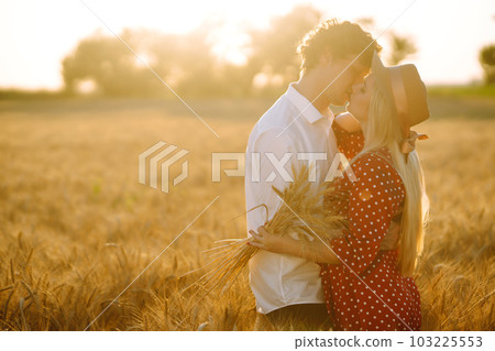 Portrait of young happy couple hugging on the field on the sunset. Enjoying time together. Portrait of young happy couple hugging on the field on the sunset. Enjoying time together. 103225553