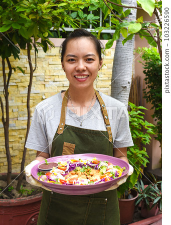 Vietnamese woman waitress serving pan fried chicken with vegetables in outdoor cafe Vietnamese woman waitress serving pan fried chicken with vegetables in outdoor cafe 103226590