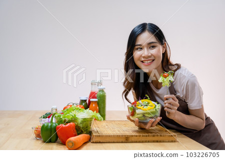 Woman eating homemade salad in kitchen. Woman eating homemade salad in kitchen. 103226705