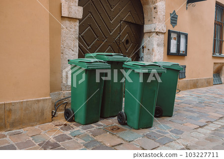 A large and small green trash can near cafe on a city street. Sorting garbage by material and type. Environmental protection, ecology. High quality photo A large and small green trash can near cafe on a city street. Sorting garbage by material and type. Environmental protection, ecology. High quality photo 103227711