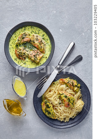 Chkmeruli on a dark plate with cutlery and gravy boats with oill and milk cream. Plate of spaghetti with fried chicken 103229405