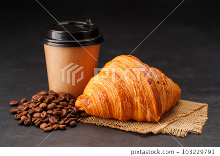 Aromatic coffee in a paper cup paired with a flaky croissant 103229791