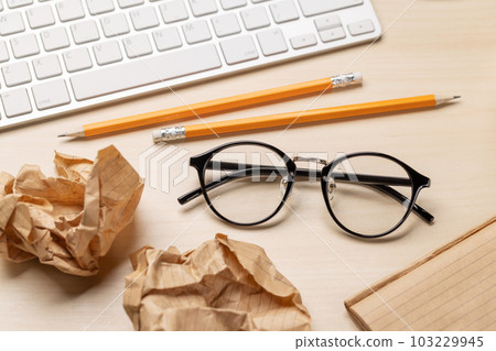 Top view of blank notepad, keyboard, eyeglasses and crumpled papers Top view of blank notepad, keyboard, eyeglasses and crumpled papers 103229945
