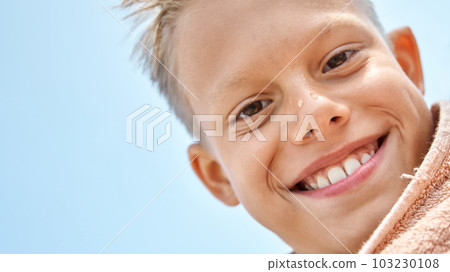 Junior schoolboy looks with delighted and happy expression after swimming. Blond boy enjoys spending summer holidays in seaside resort 103230108
