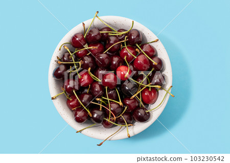 Fresh sweet cherries bowl isolated on blue background. Top view 103230542