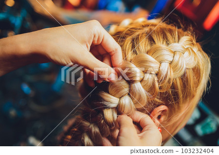 Process of braiding the master weaves braids on her head blond little girl in beauty salon close up. Professional hair care and creating hairstyles. Process of braiding the master weaves braids on her head blond little girl in beauty salon close up. Professional hair care and creating hairstyles. 103232404