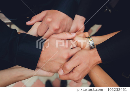 two man and three women holding hands on a table implying a polyamory relationship or love triangle. two man and three women holding hands on a table implying a polyamory relationship or love triangle. 103232461